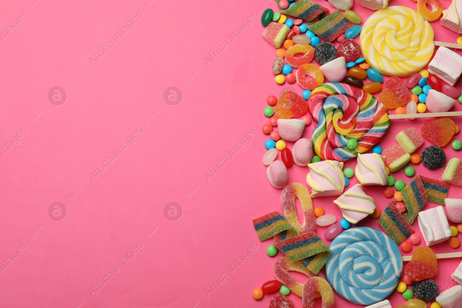 Photo of Different delicious candies and marshmallows on pink background, flat lay. Space for text