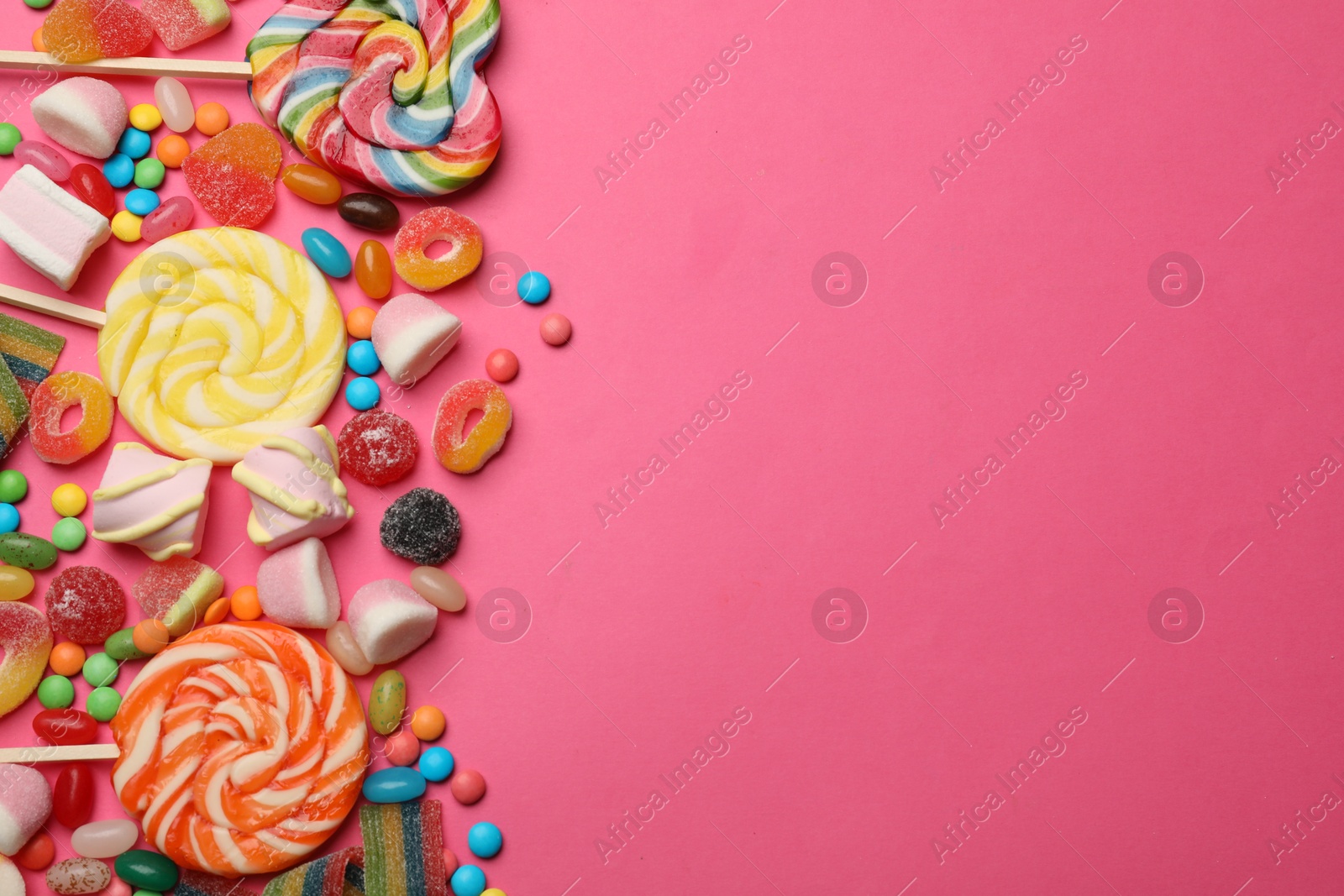 Photo of Different delicious candies and marshmallows on pink background, flat lay. Space for text