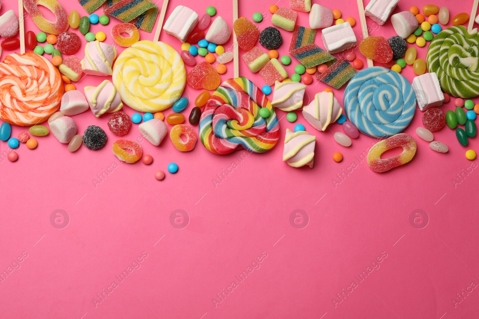 Photo of Different delicious candies and marshmallows on pink background, flat lay. Space for text