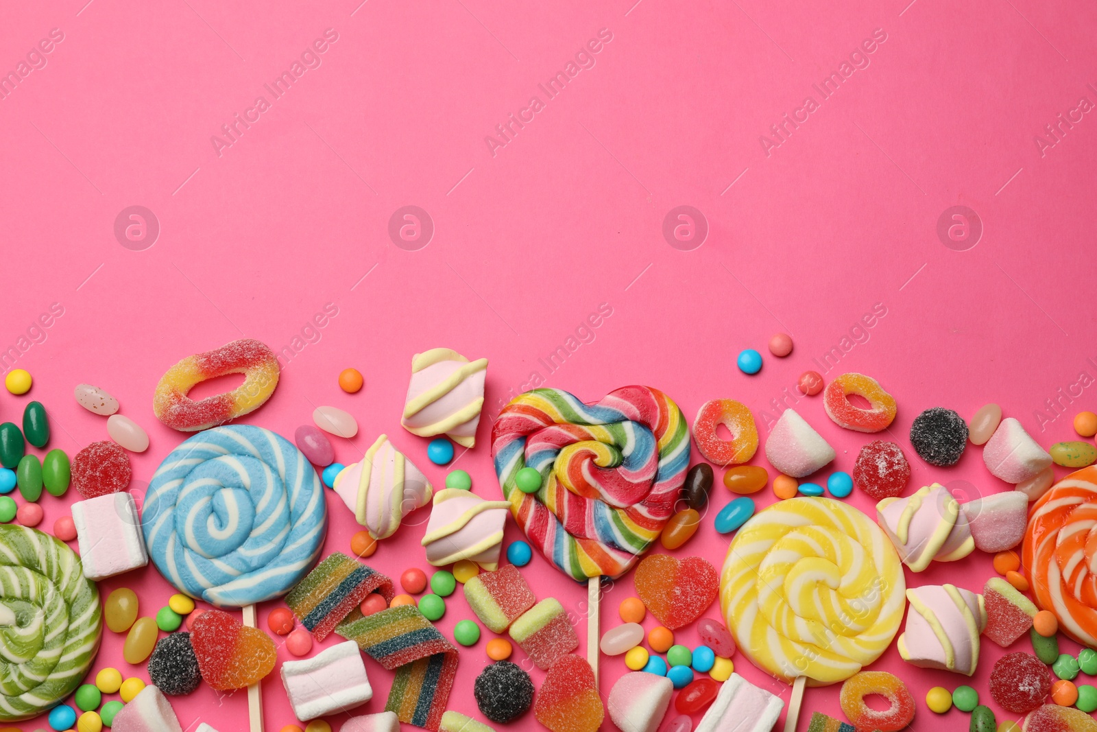 Photo of Different delicious candies and marshmallows on pink background, flat lay. Space for text