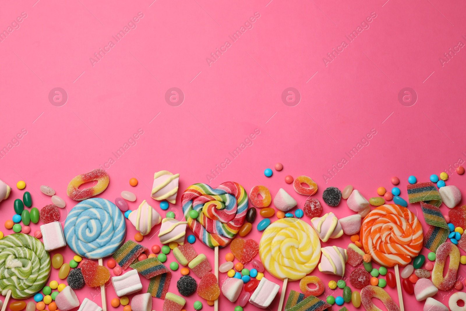 Photo of Different delicious candies and marshmallows on pink background, flat lay. Space for text