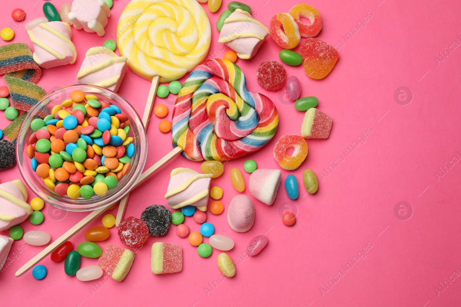 Photo of Different delicious candies and marshmallows on pink background, flat lay