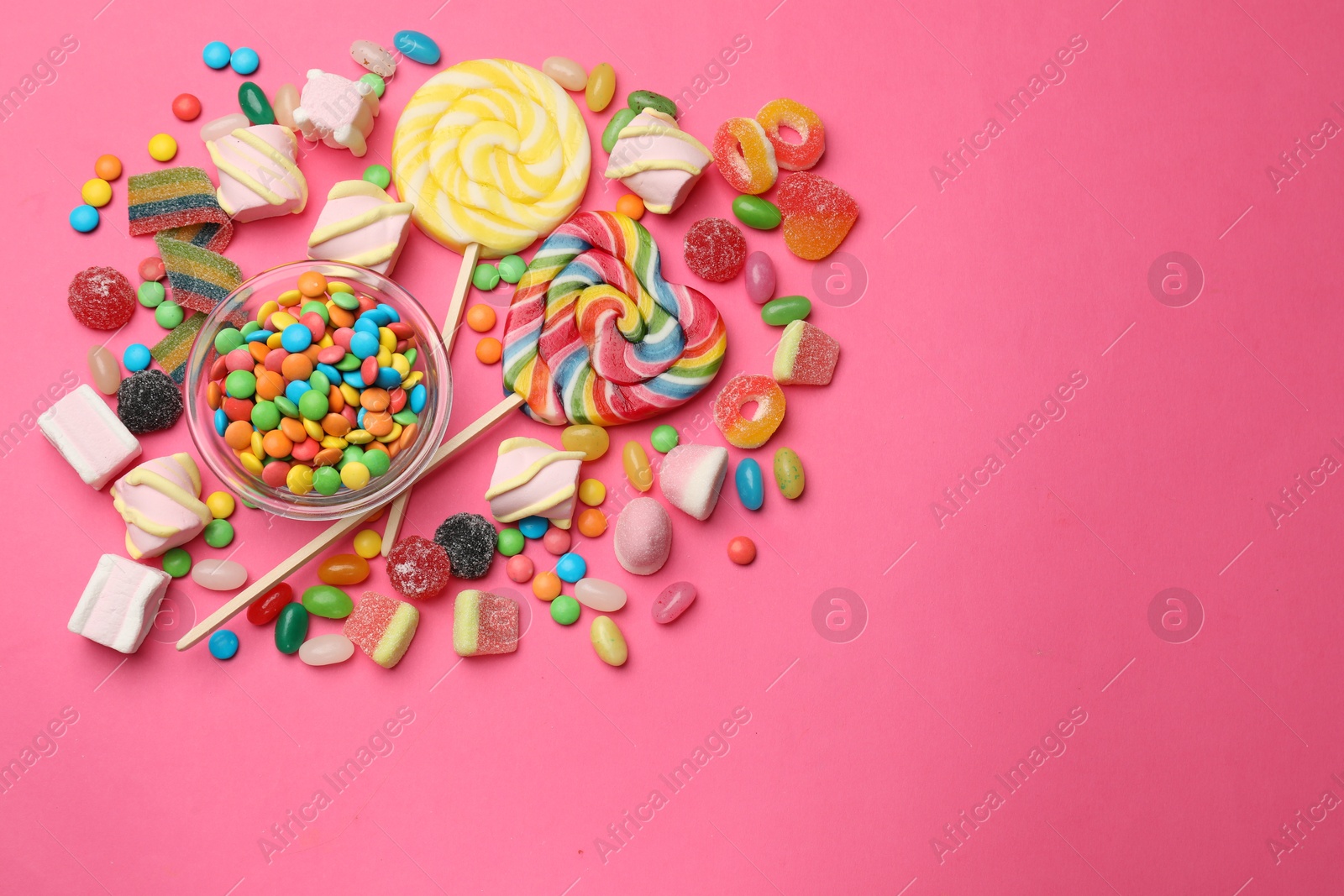 Photo of Different delicious candies and marshmallows on pink background, flat lay. Space for text