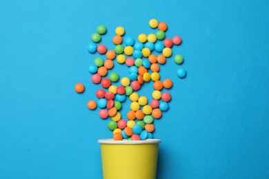 Photo of Colorful sugar coated dragee candies on blue background, top view