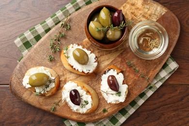 Photo of Delicious sandwiches with cream cheese and marinated olives on wooden table