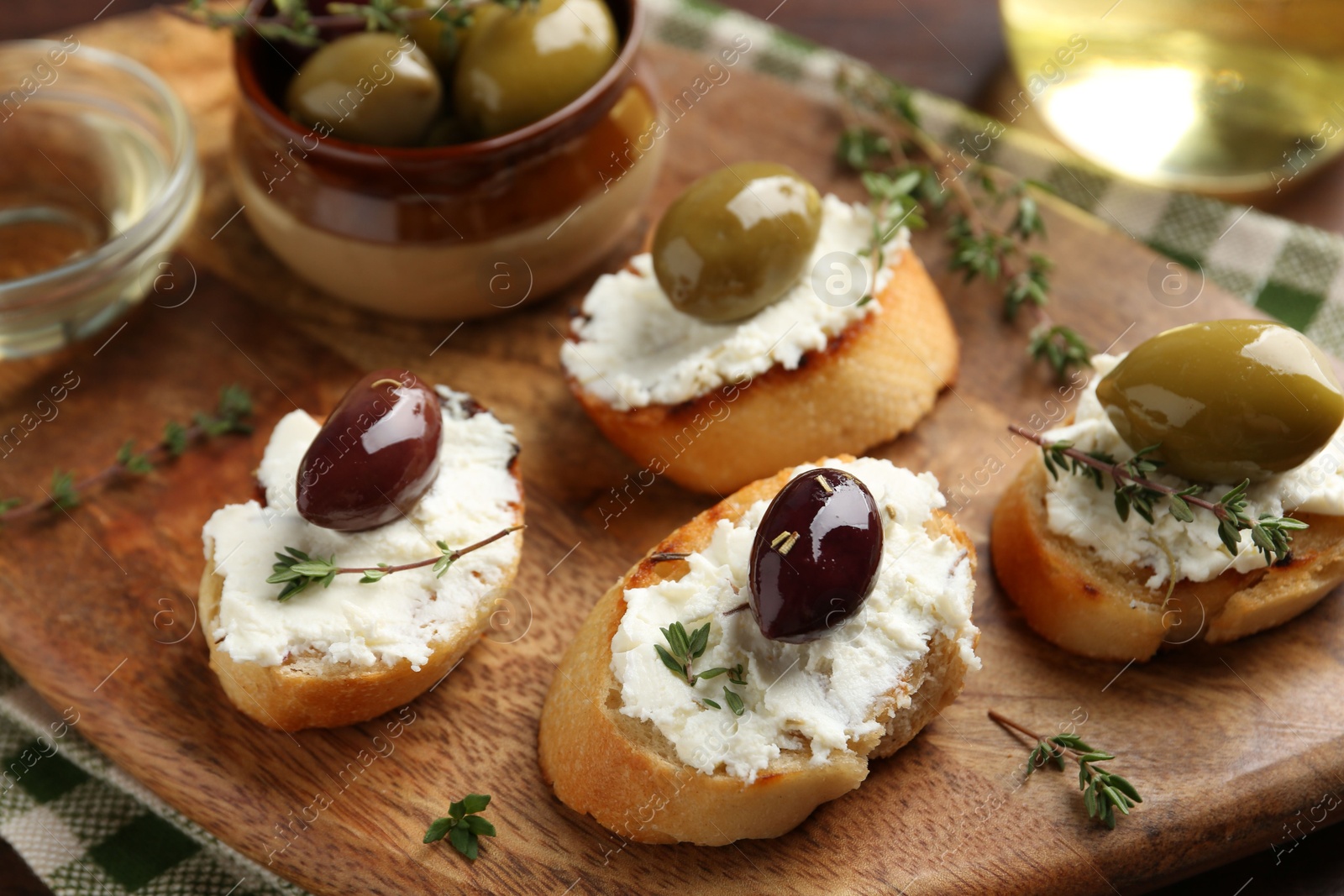 Photo of Delicious sandwiches with cream cheese and marinated olives on wooden table