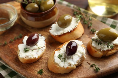 Photo of Delicious sandwiches with cream cheese and marinated olives on wooden table