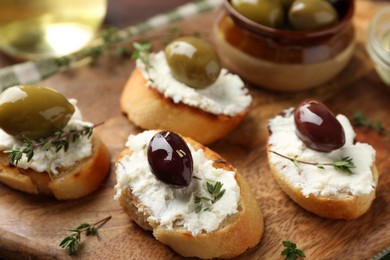 Photo of Delicious sandwiches with cream cheese and marinated olives on wooden table