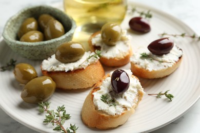 Photo of Delicious sandwiches with cream cheese and marinated olives on light table