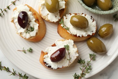 Photo of Delicious sandwiches with cream cheese and marinated olives on light table