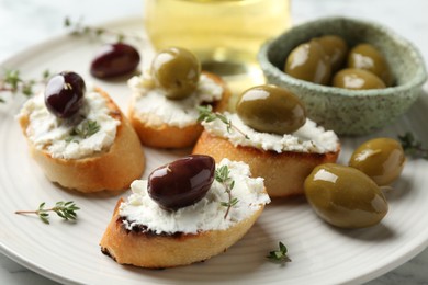 Photo of Delicious sandwiches with cream cheese and marinated olives on light table