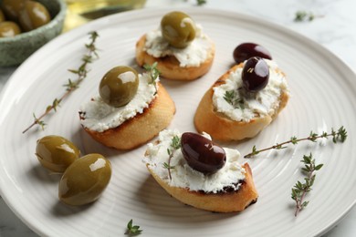 Photo of Delicious sandwiches with cream cheese and marinated olives on light table