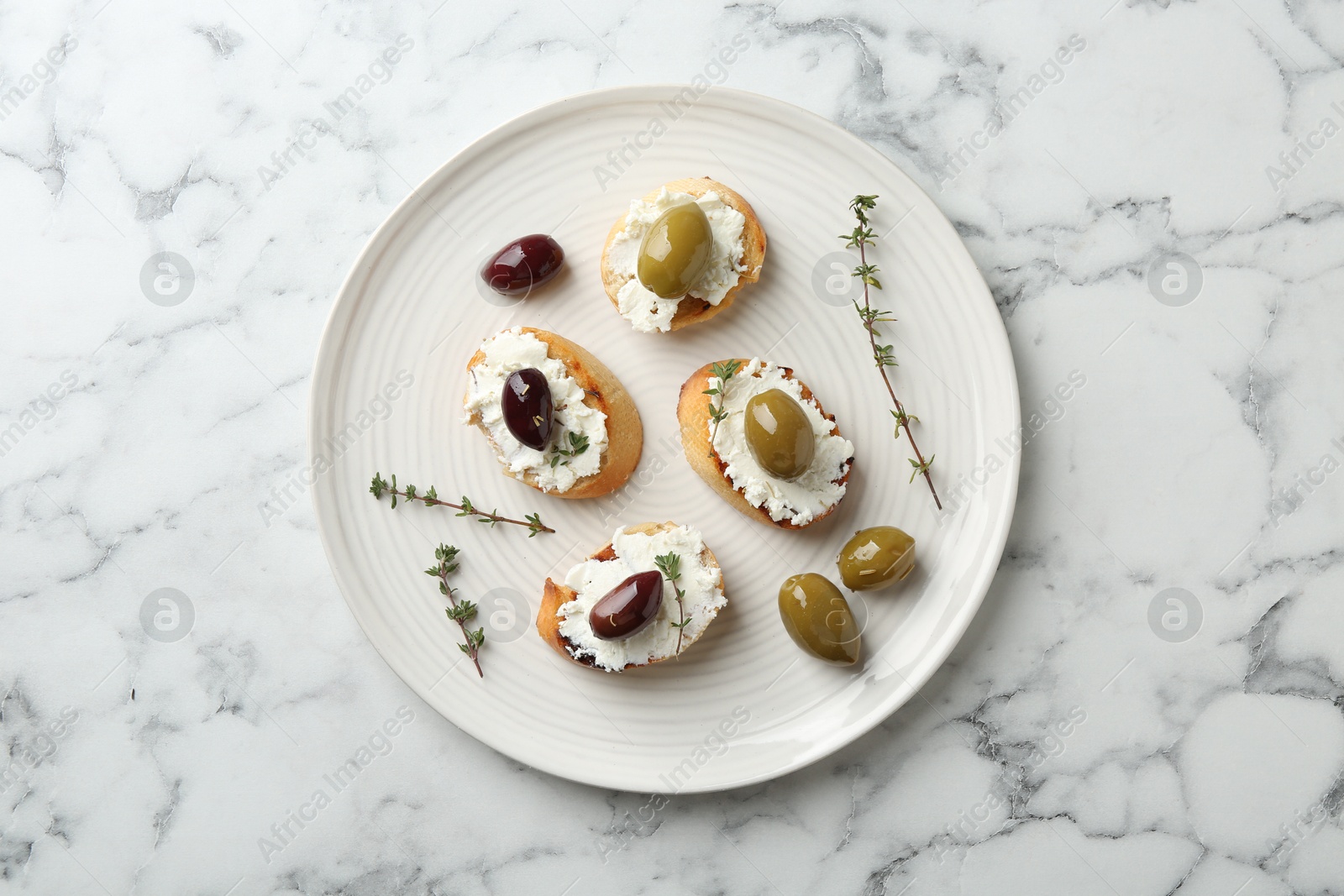 Photo of Delicious sandwiches with cream cheese and marinated olives on white marble table