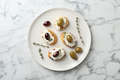 Photo of Delicious sandwiches with cream cheese and marinated olives on white marble table