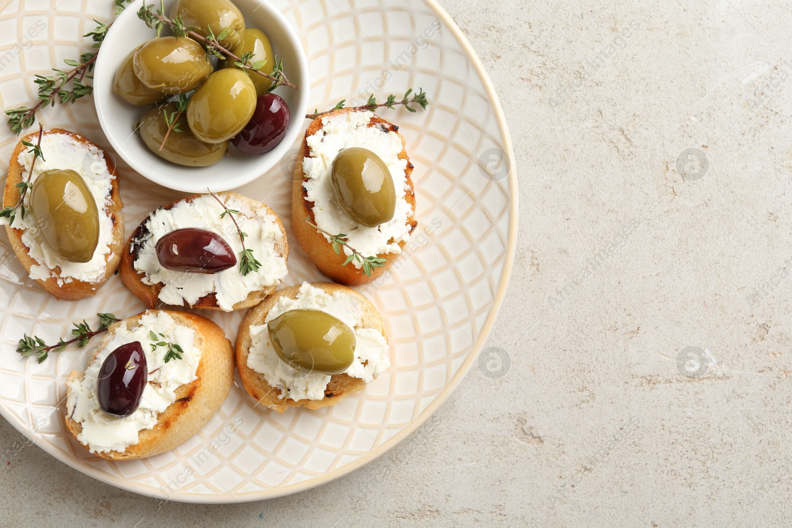 Photo of Delicious sandwiches with cream cheese and marinated olives on light table. Space for text