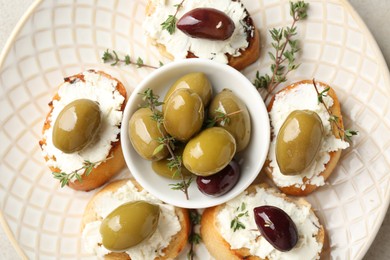 Photo of Delicious sandwiches with cream cheese and marinated olives on light table, top view