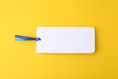 Photo of One paper bookmark on yellow background, top view