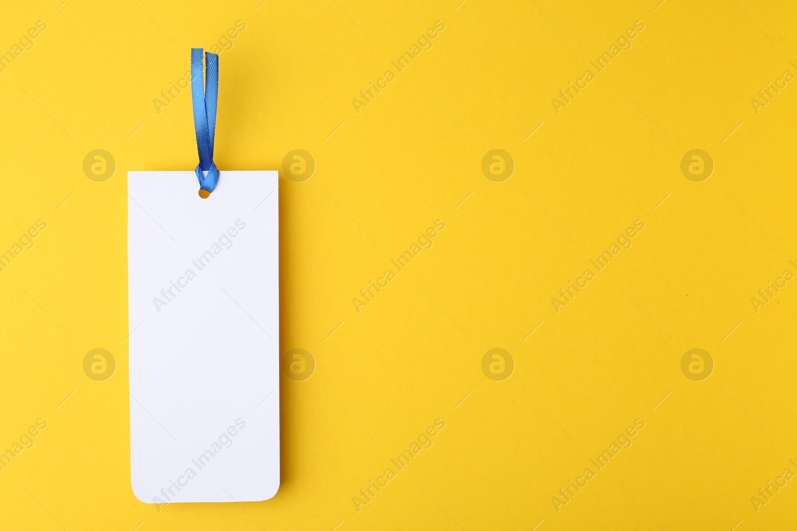 Photo of One paper bookmark on yellow background, top view. Space for text