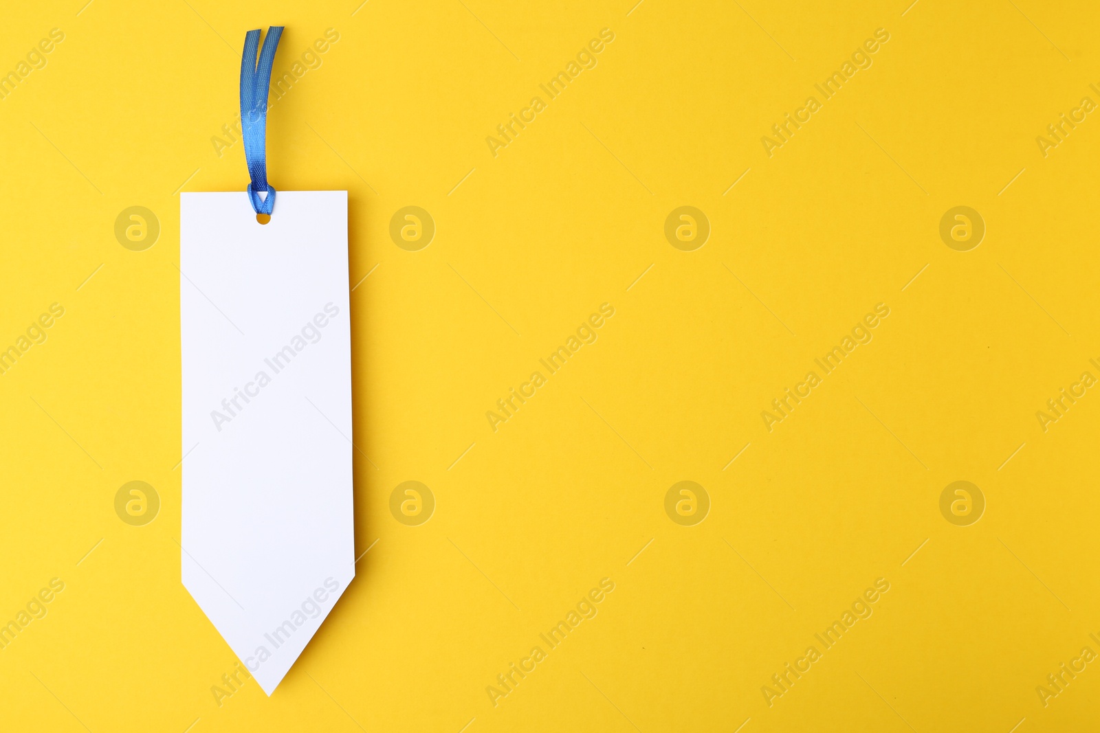 Photo of One paper bookmark on yellow background, top view. Space for text