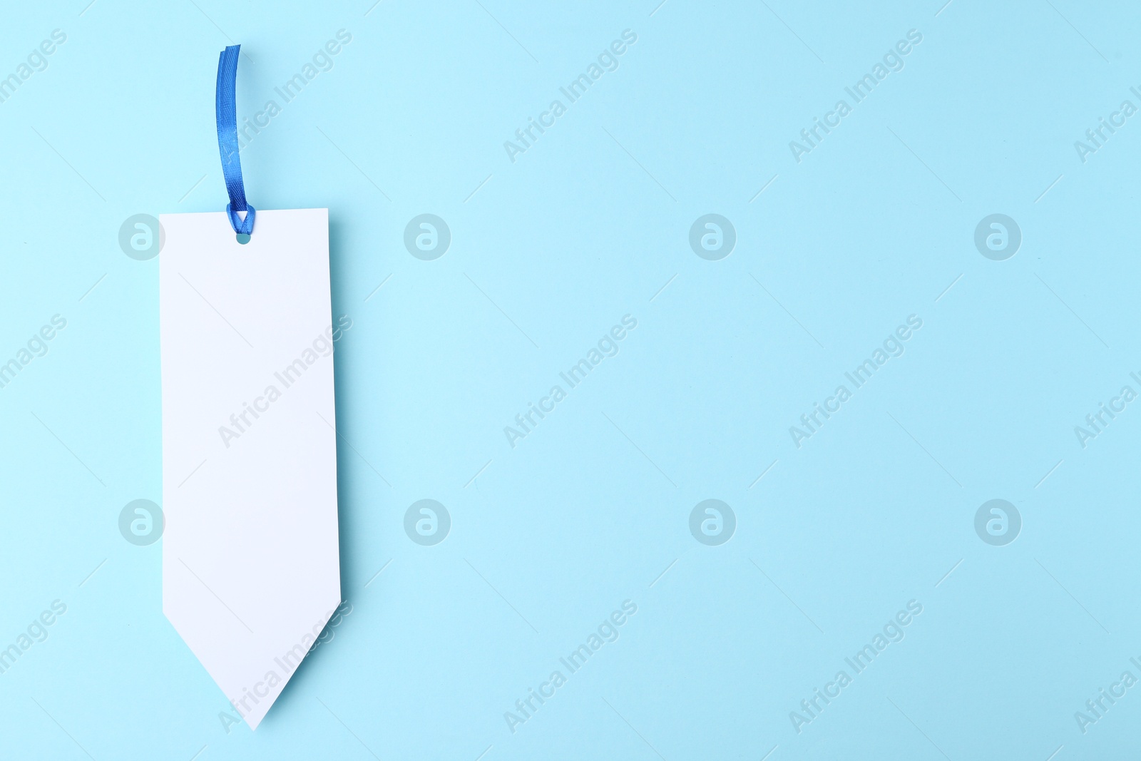 Photo of One paper bookmark on light blue background, top view. Space for text