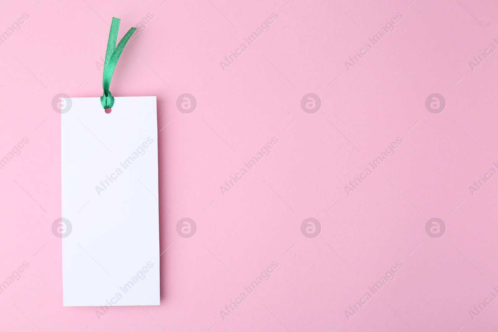 Photo of One paper bookmark on pink background, top view. Space for text