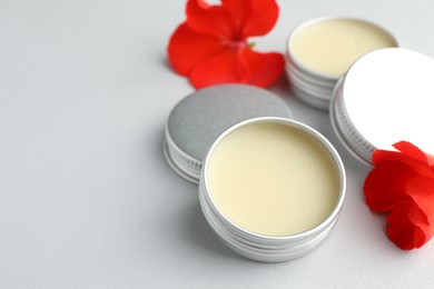 Photo of Lip balms and red flowers on white background, closeup. Space for text