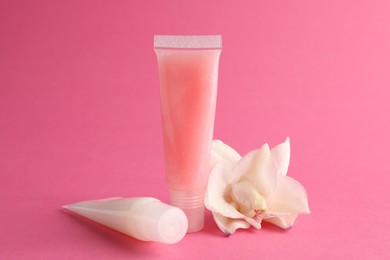 Photo of Lip balms and flower on pink background, closeup