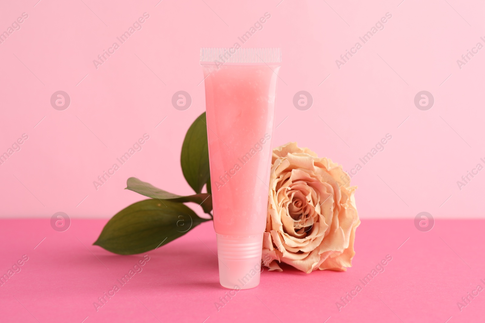 Photo of Lip balm and flower on pink background, closeup