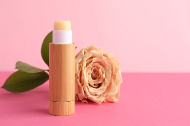 Photo of Lip balm and flower on pink background, closeup. Space for text