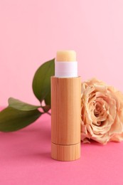 Photo of Lip balm and flower on pink background, closeup