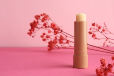 Photo of Lip balm and flowers on pink background, closeup. Space for text