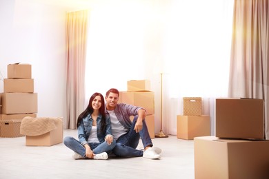 Image of Happy couple in sunlit room with cardboard boxes on moving day