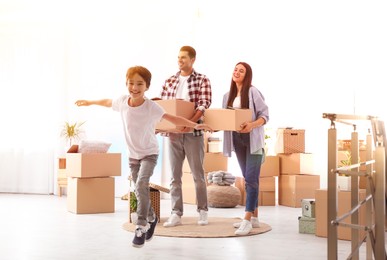 Happy family in sunlit room with cardboard boxes on moving day