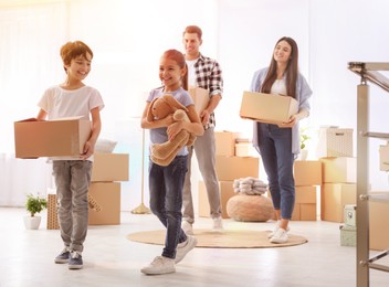 Happy family in sunlit room with cardboard boxes on moving day