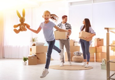 Happy family in sunlit room with cardboard boxes on moving day