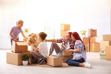 Image of Happy family in sunlit room with cardboard boxes on moving day