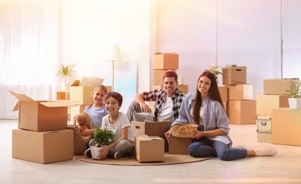 Image of Happy family in sunlit room with cardboard boxes on moving day