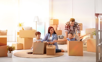 Image of Happy family in sunlit room with cardboard boxes on moving day