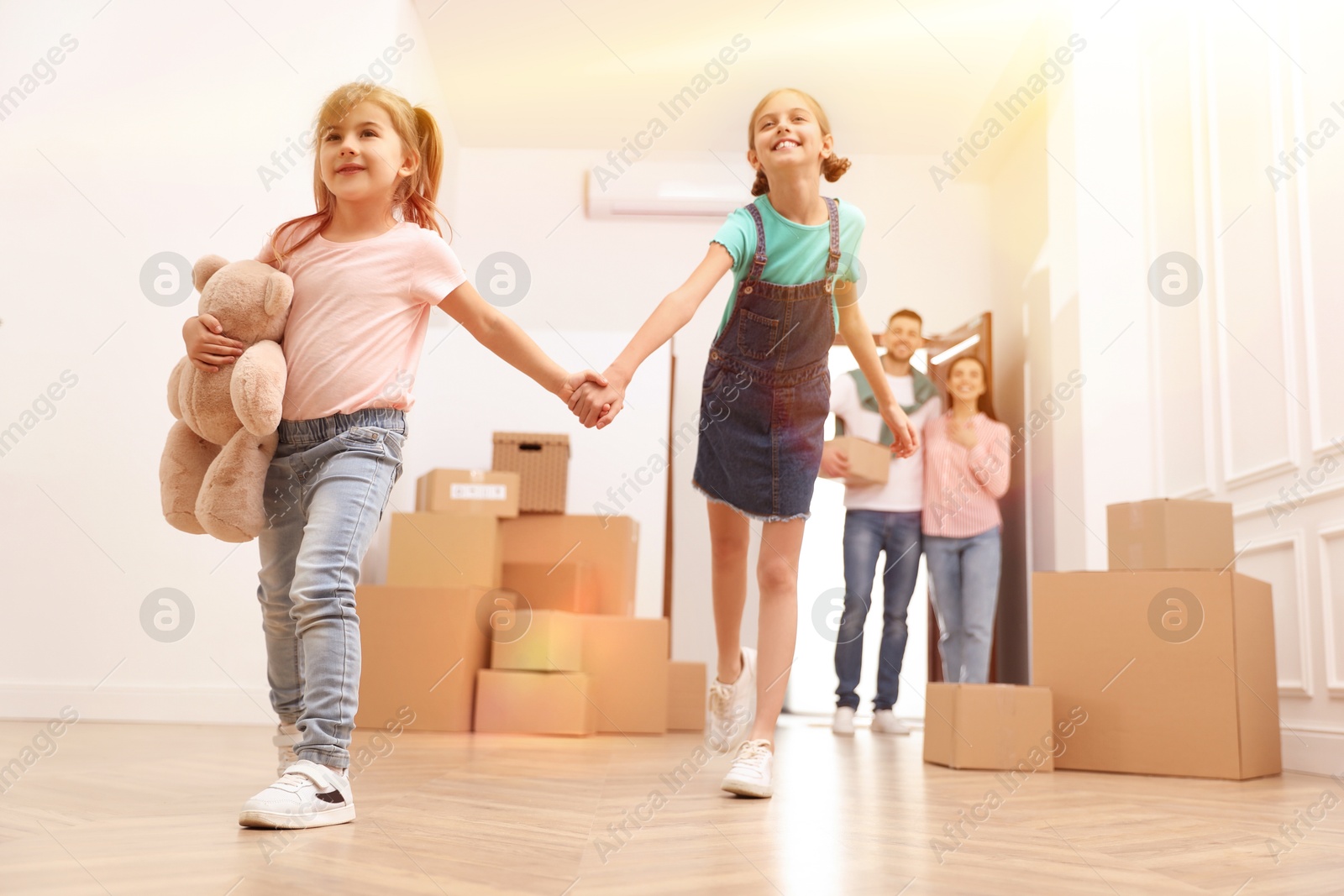 Image of Happy family in sunlit room with cardboard boxes on moving day, low angle view