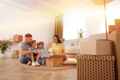 Image of Happy family in sunlit room with cardboard boxes on moving day