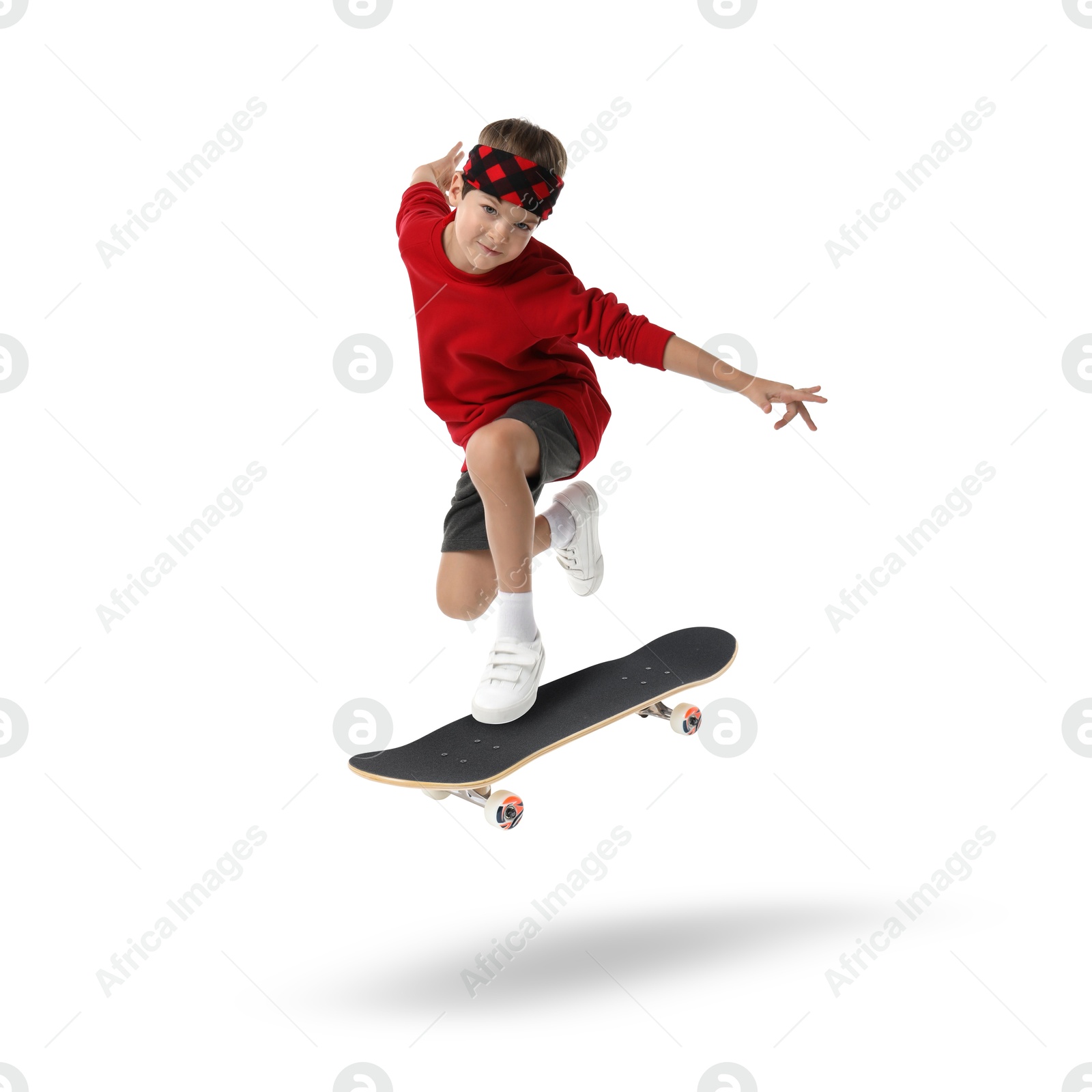 Image of Cute little boy with skateboard in air on white background. Performing trick