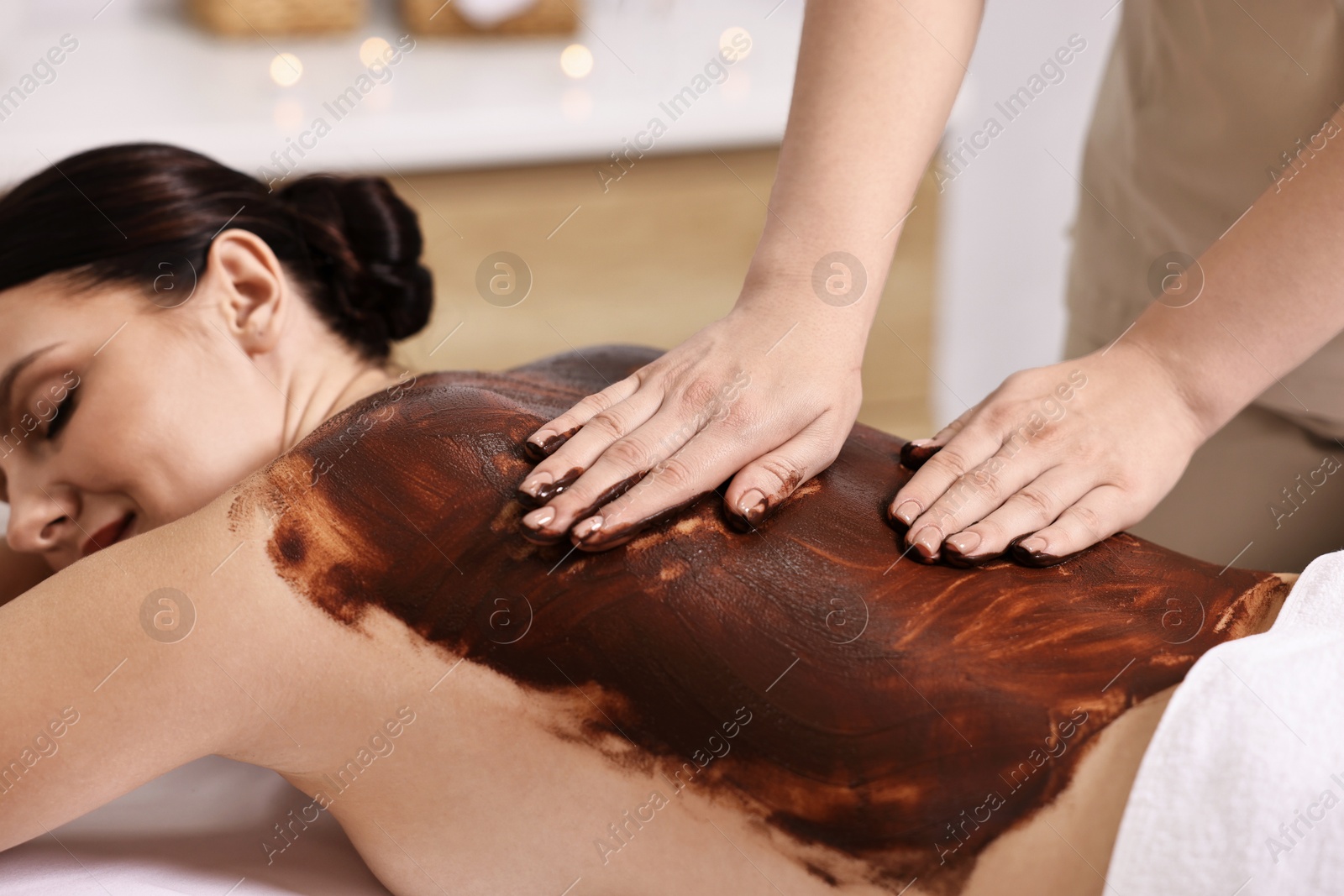 Photo of Woman undergoing chocolate body wrap treatment in spa salon