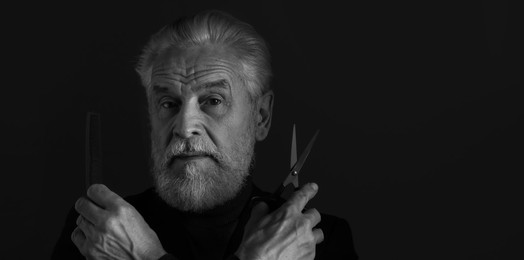 Photo of Bearded man with scissors and comb on dark background, space for text. Black and white effect