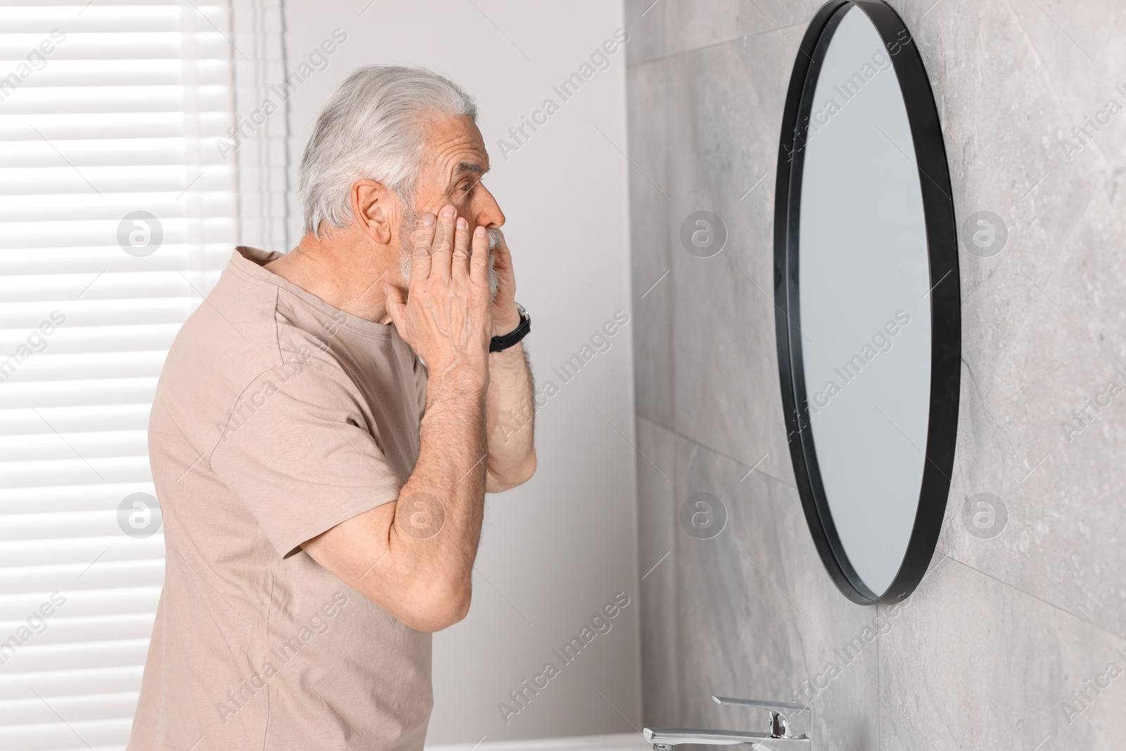 Photo of Bearded senior man near mirror in bathroom