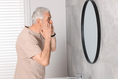 Photo of Bearded senior man near mirror in bathroom