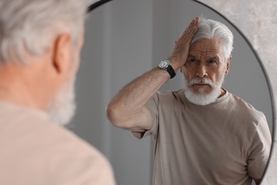 Photo of Handsome bearded man near mirror in bathroom