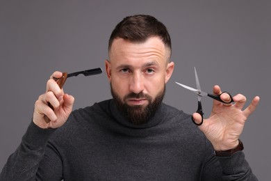 Photo of Bearded man holding blade and scissors on grey background