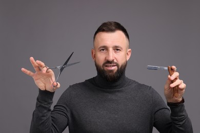 Photo of Bearded man holding blade and scissors on grey background