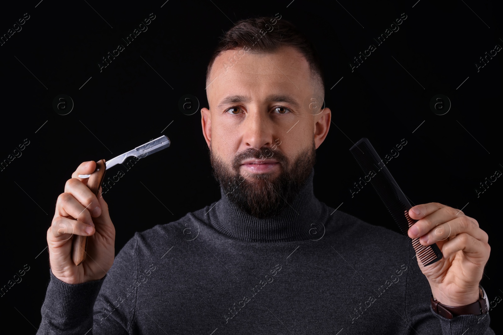 Photo of Bearded man holding blade and scissors on black background