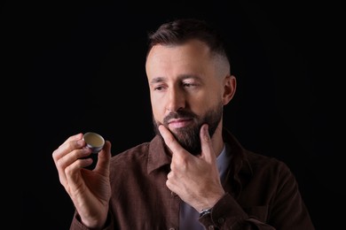 Photo of Handsome bearded man with balm on black background